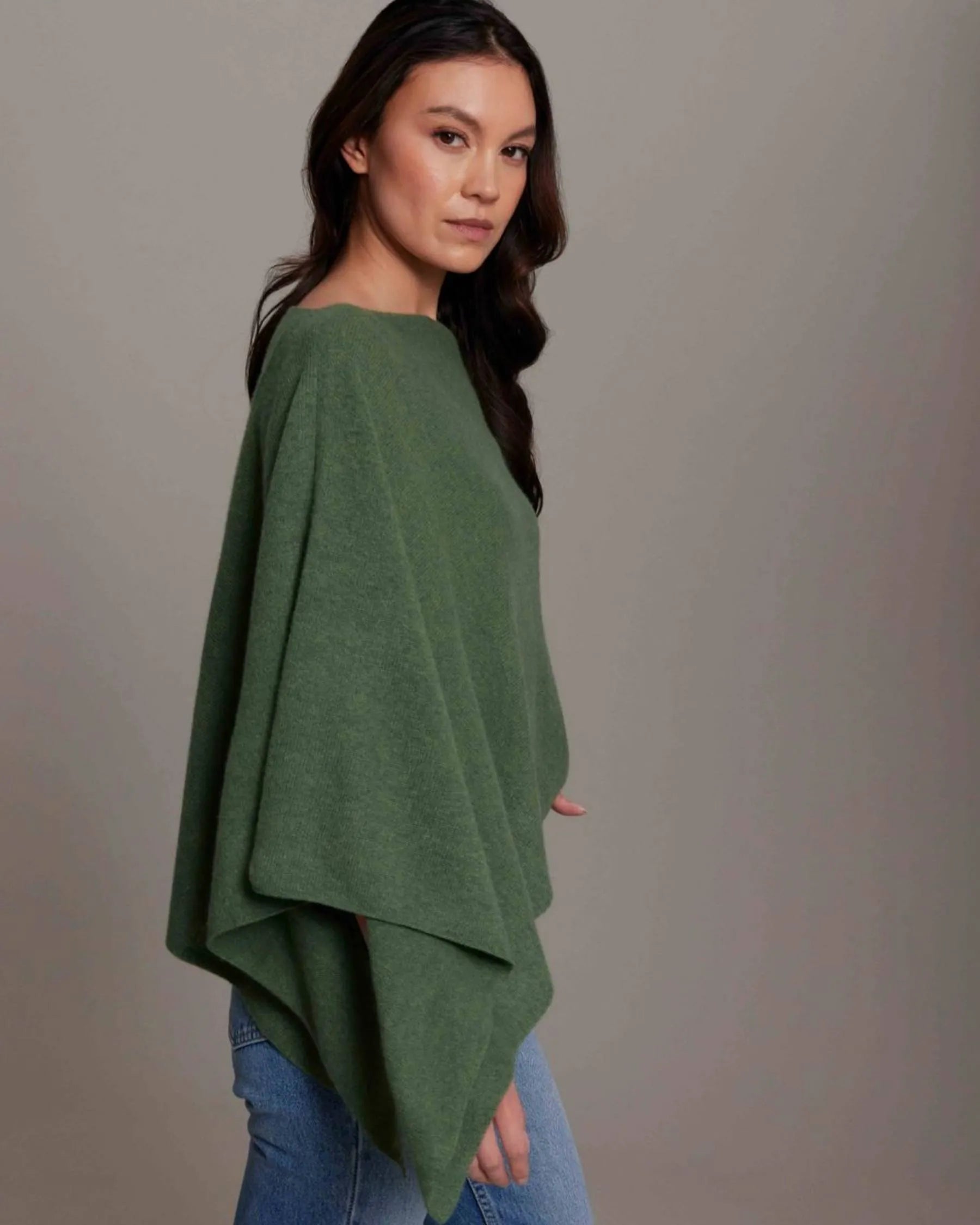 Woman wearing a green poncho against a gray background
