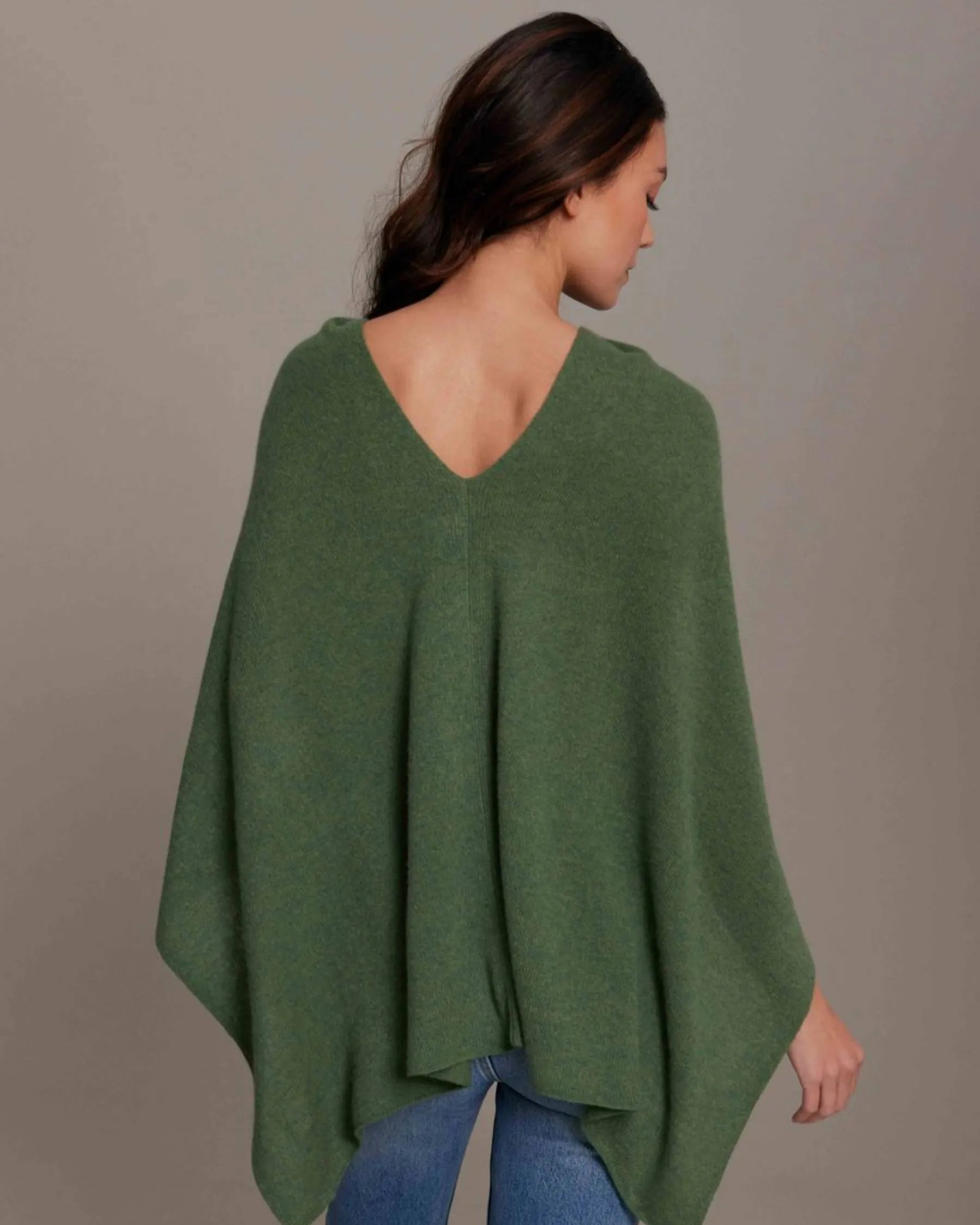 Woman wearing a green poncho against a plain background