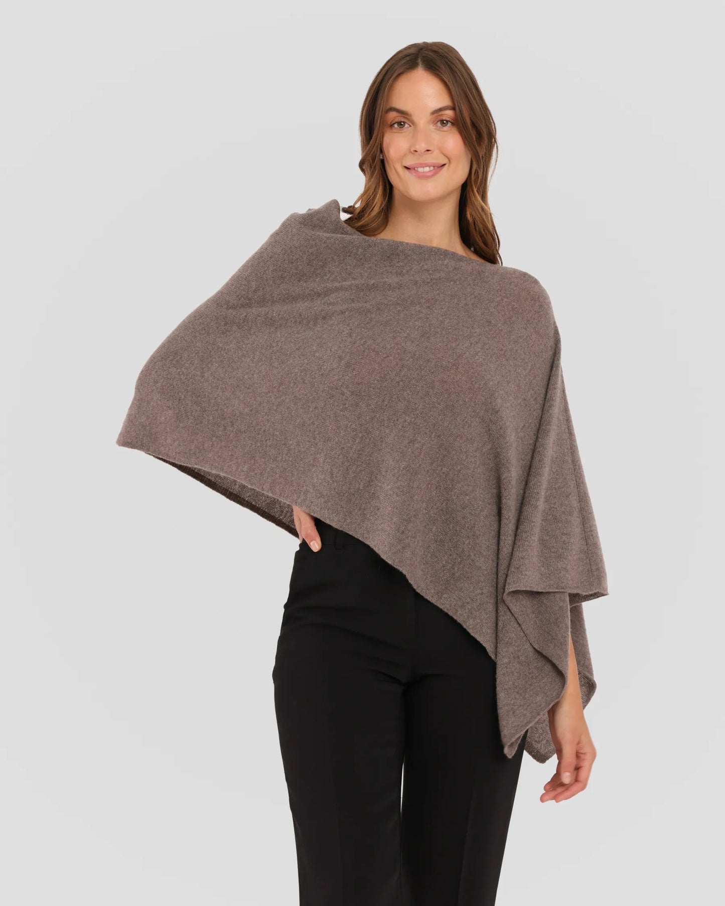 Woman wearing a brown poncho against a plain background