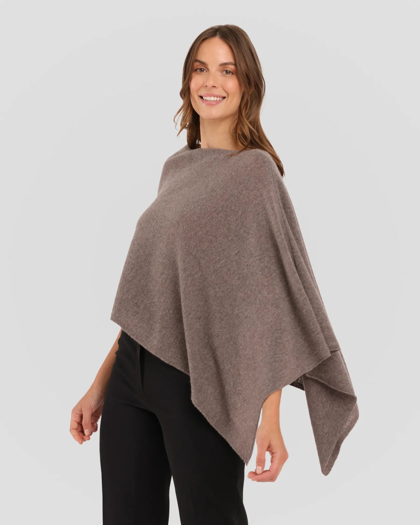 Woman wearing a brown poncho against a plain background