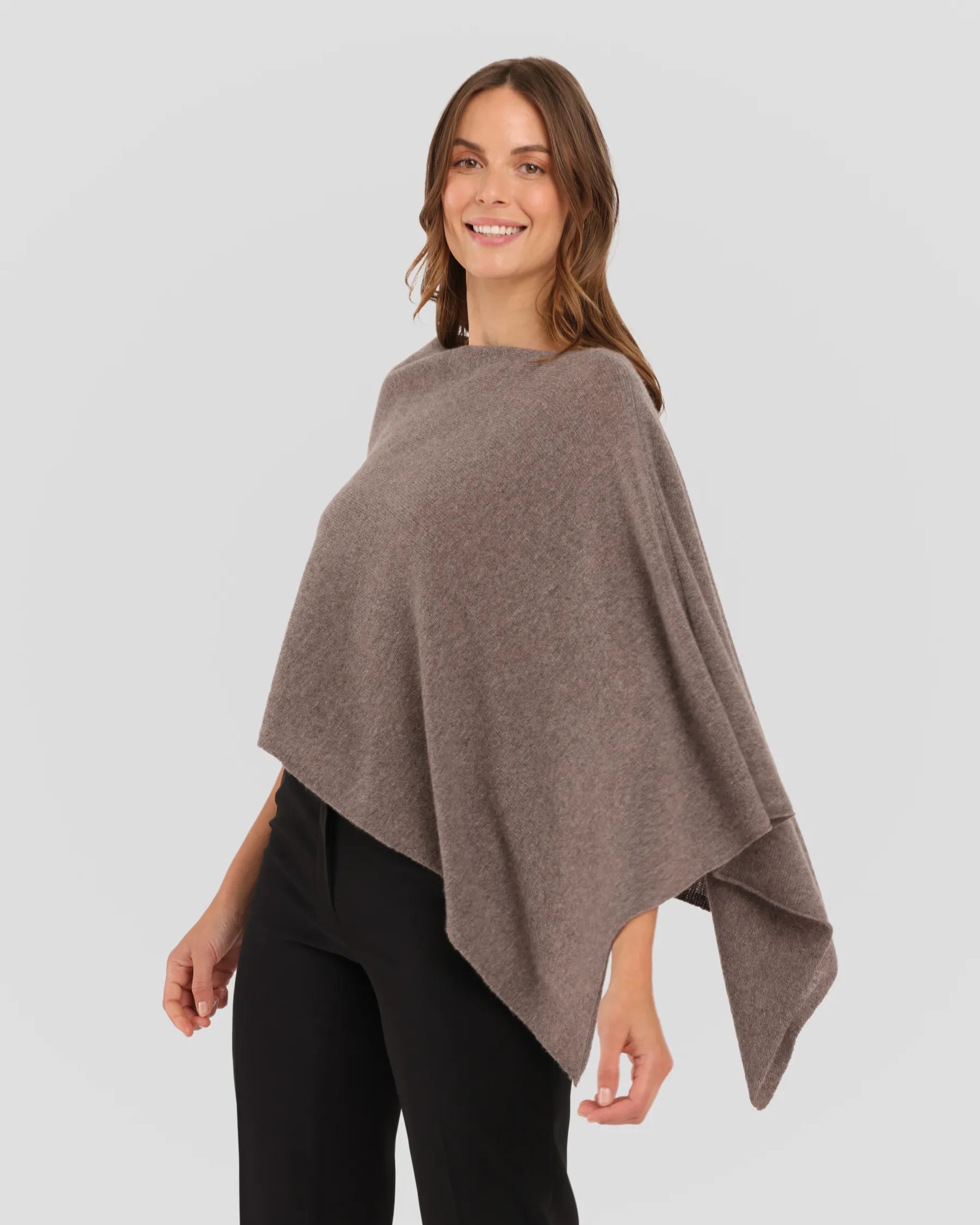 Woman wearing a brown poncho against a plain background