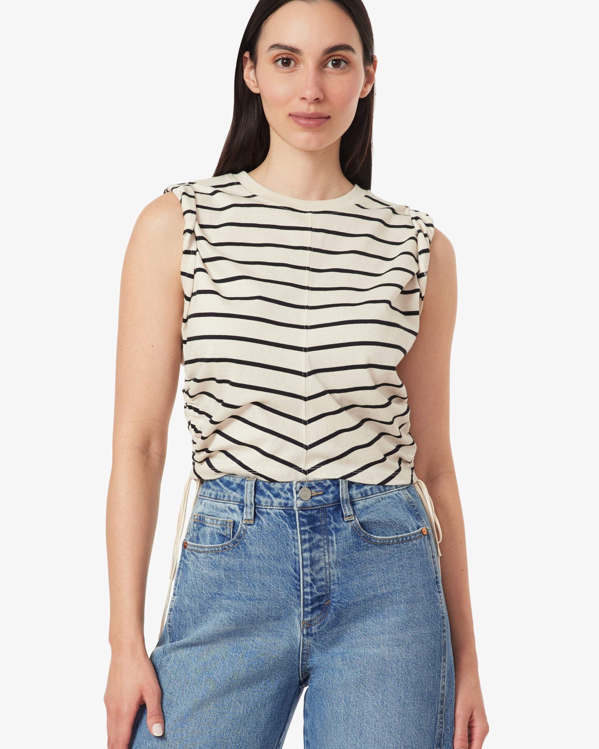 Woman wearing a striped sleeveless top and jeans on a white background