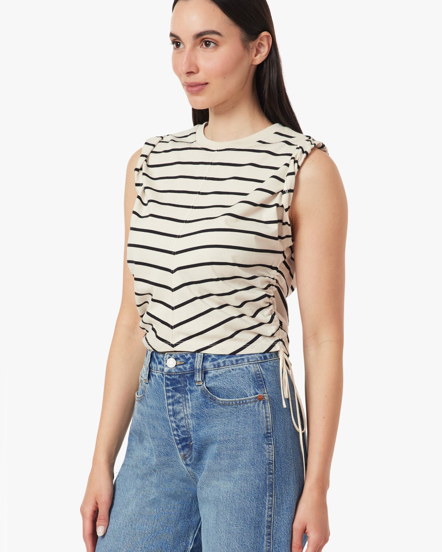 Woman wearing a sleeveless striped top and blue jeans on a white background