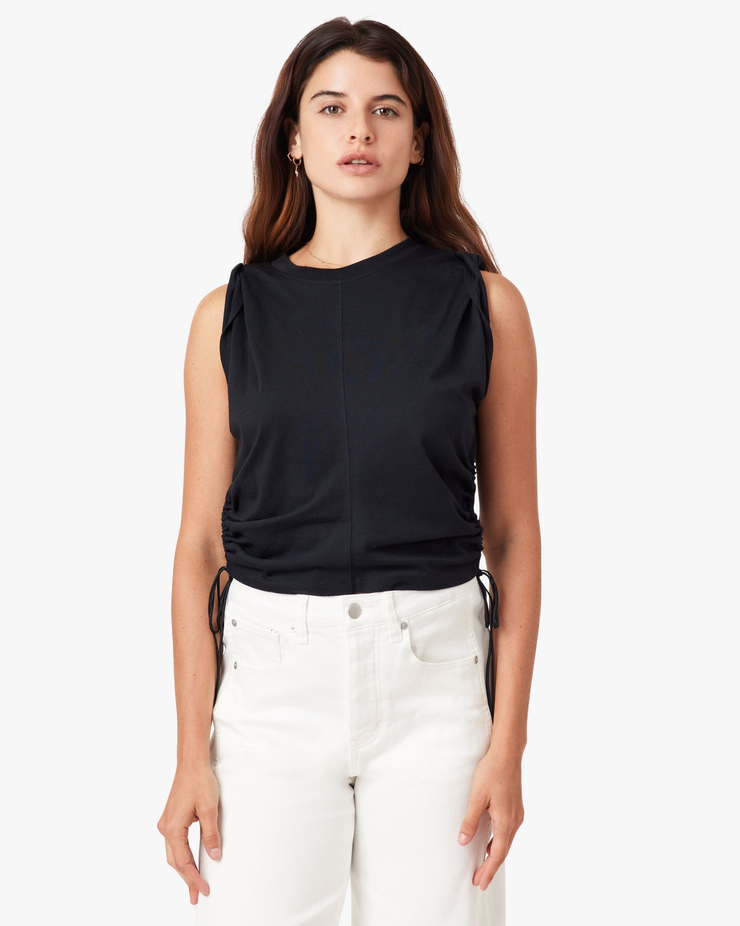 Woman wearing a black sleeveless top and white pants on a white background