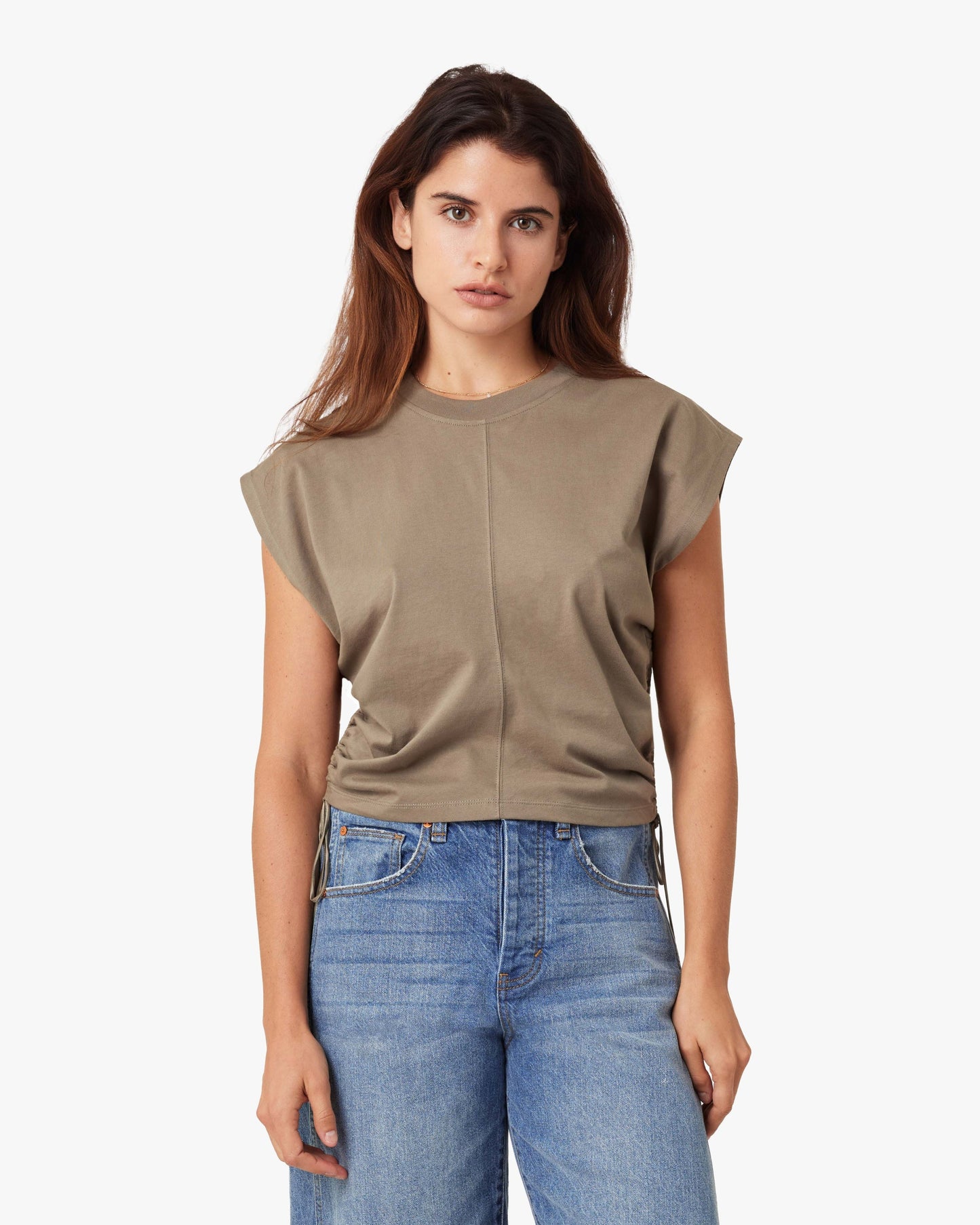 Woman wearing a beige top and blue jeans on a white background