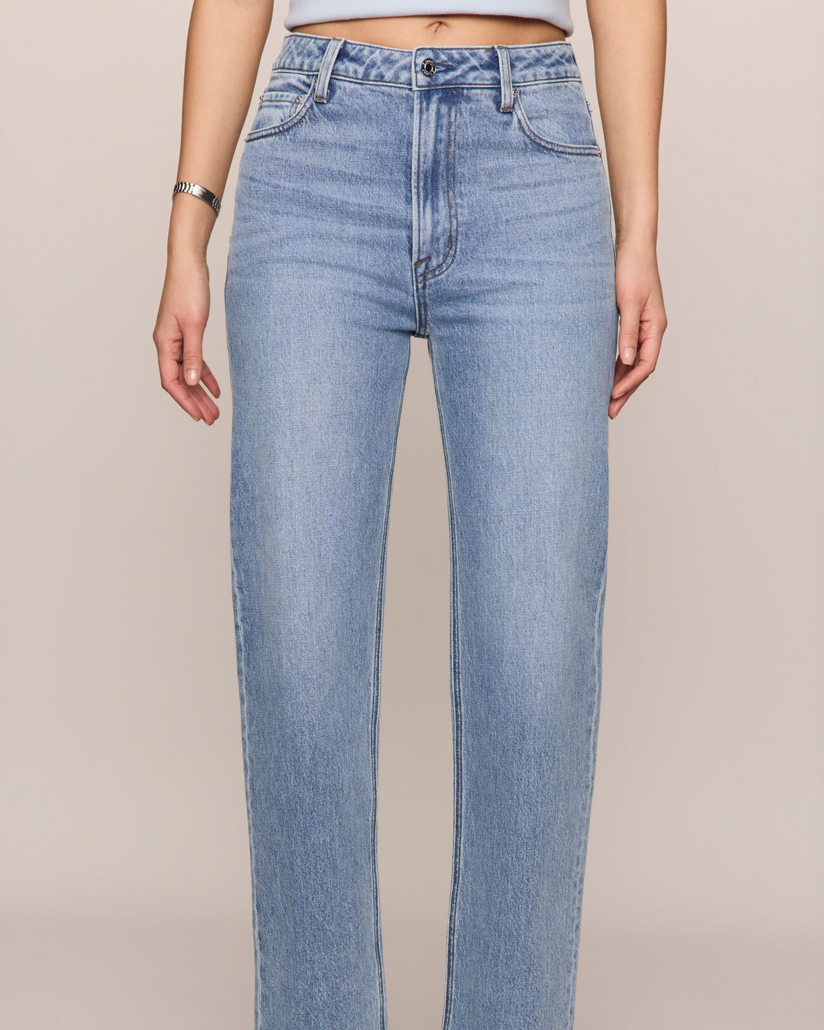 Light blue jeans worn by a person on a beige background