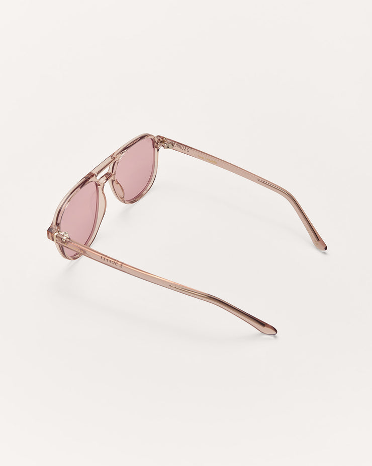 Sunglasses with rose gold frame and pink lenses on a light beige background