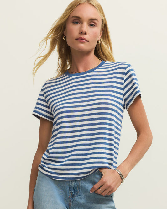 Woman wearing a blue and white striped t-shirt and light blue jeans against a plain background