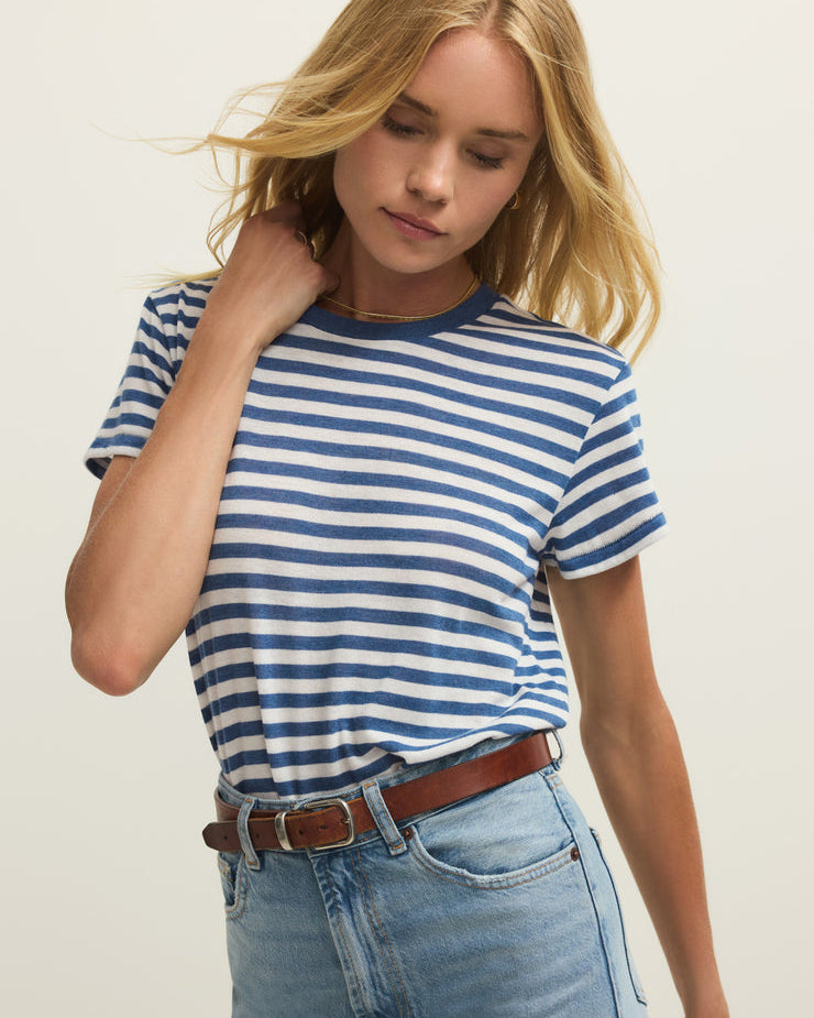 Woman wearing a blue and white striped shirt and light blue jeans against a plain background