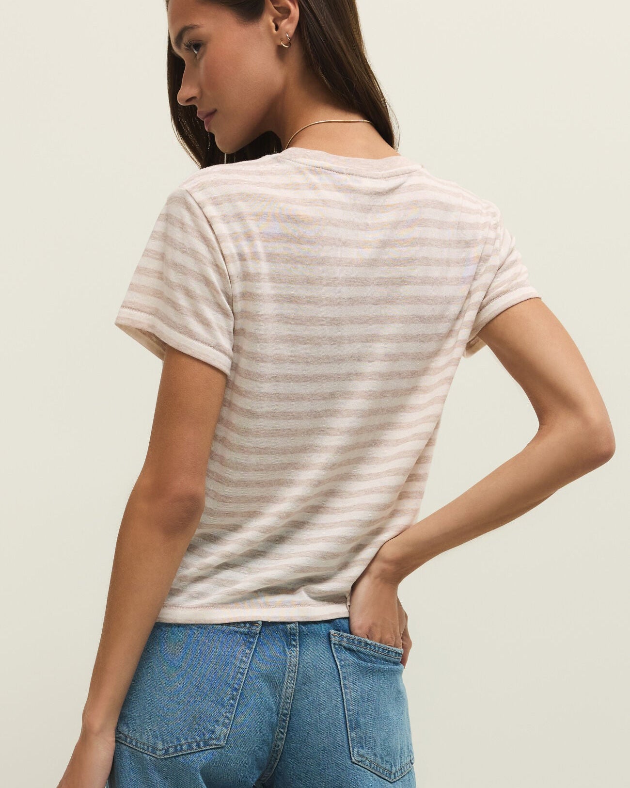 Woman wearing a striped t-shirt and blue jeans against a plain background