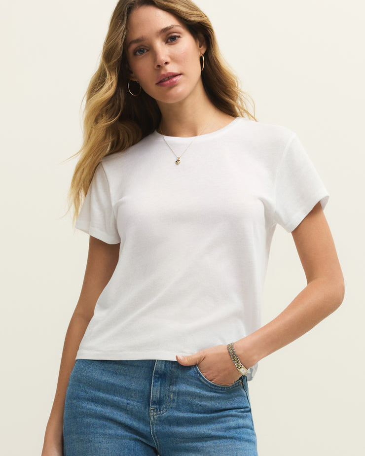 Woman wearing a white t-shirt and blue jeans against a plain background