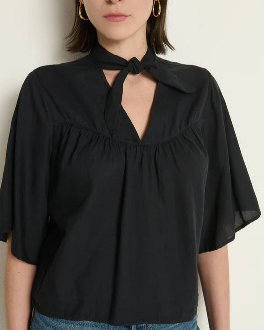 Black blouse with a tie neckline worn by a person on a plain background