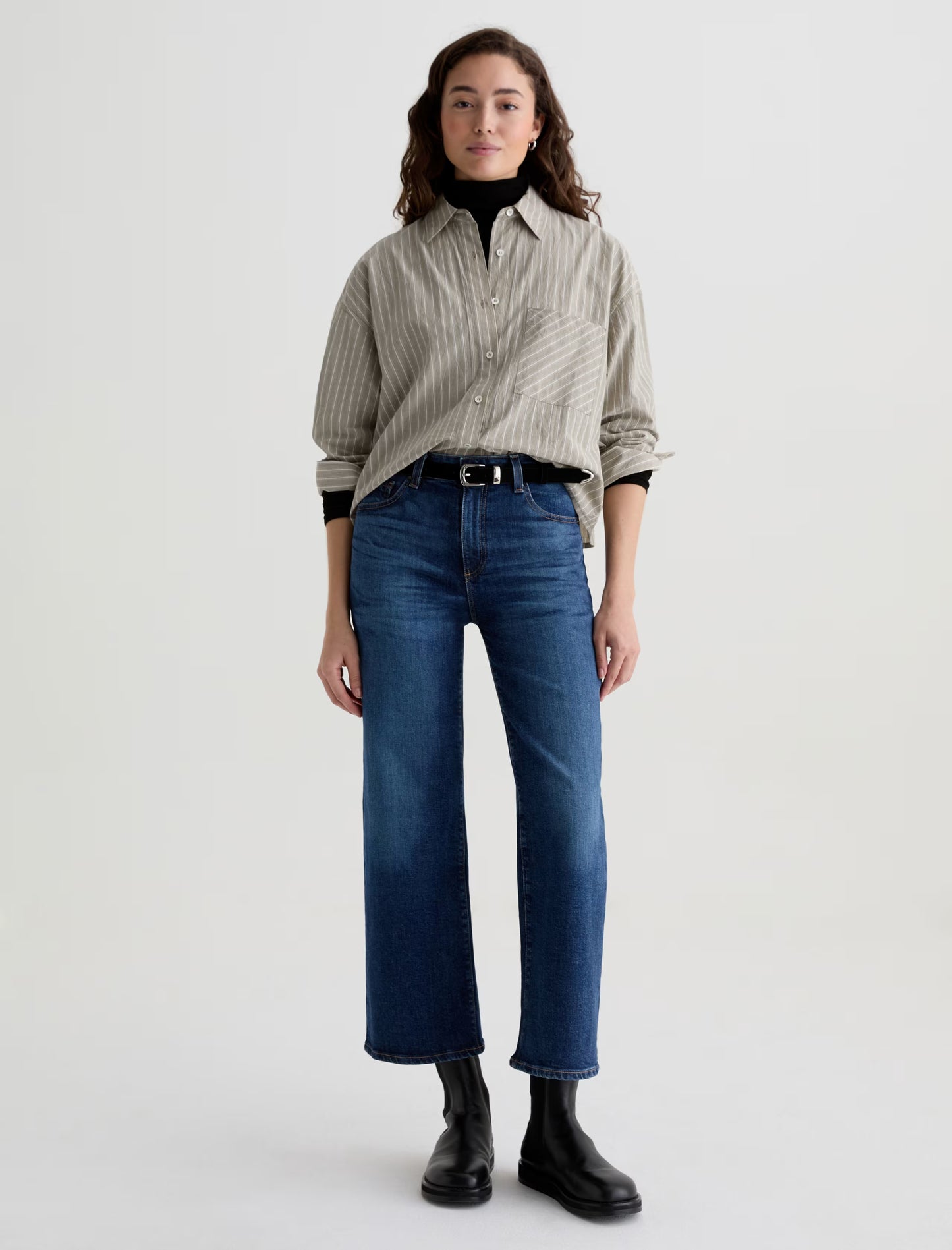 Person wearing a striped shirt, blue jeans, and black boots on a white background