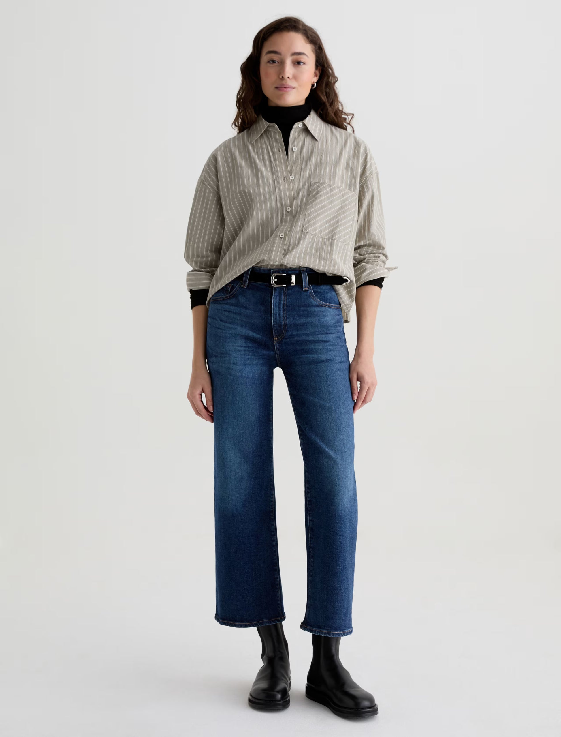 Person wearing a striped shirt, blue jeans, and black boots on a white background