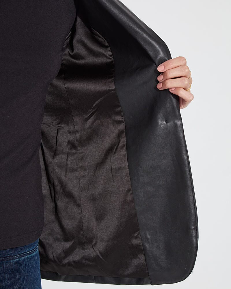 Person holding a black leather jacket against a white background