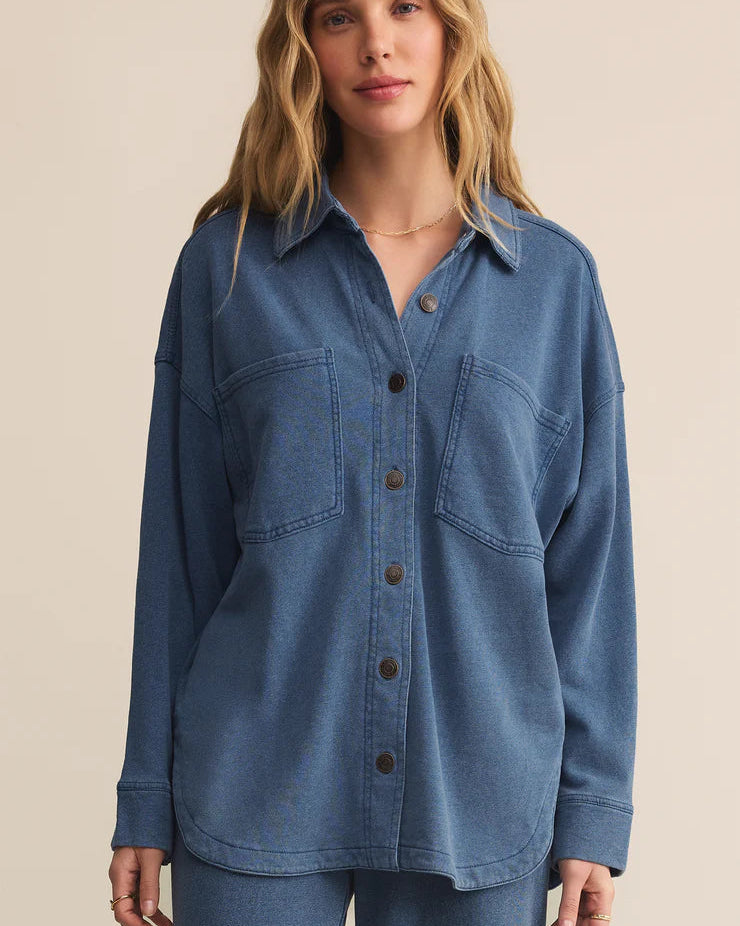 Woman wearing a blue denim shirt against a beige background