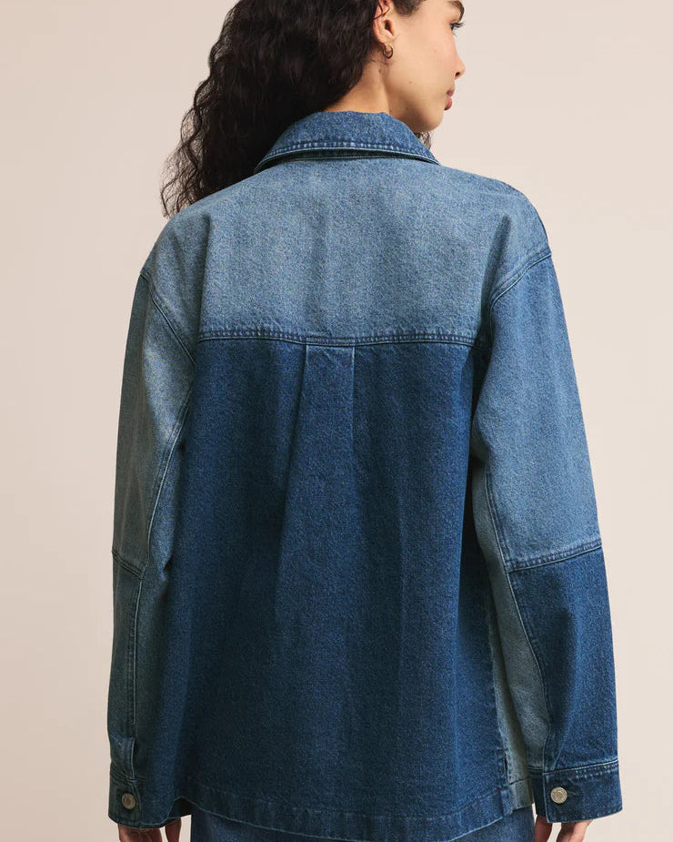 Woman wearing a blue denim jacket on a beige background