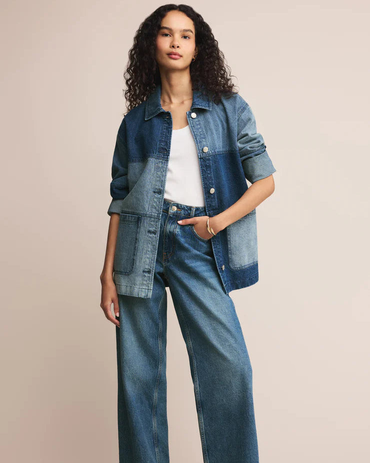 Woman wearing a denim jacket and jeans on a beige background
