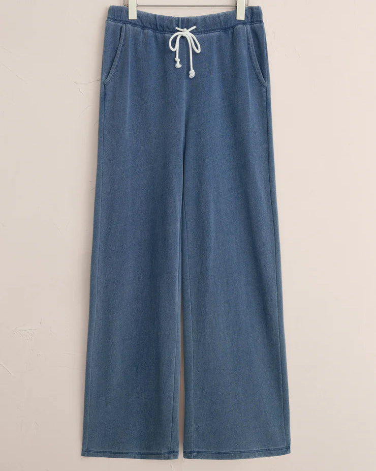 Blue wide-leg pants with a drawstring on a hanger against a beige background