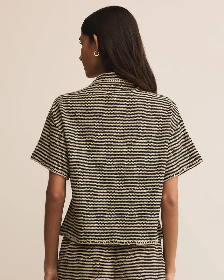 Person wearing a black and white striped outfit on a beige background