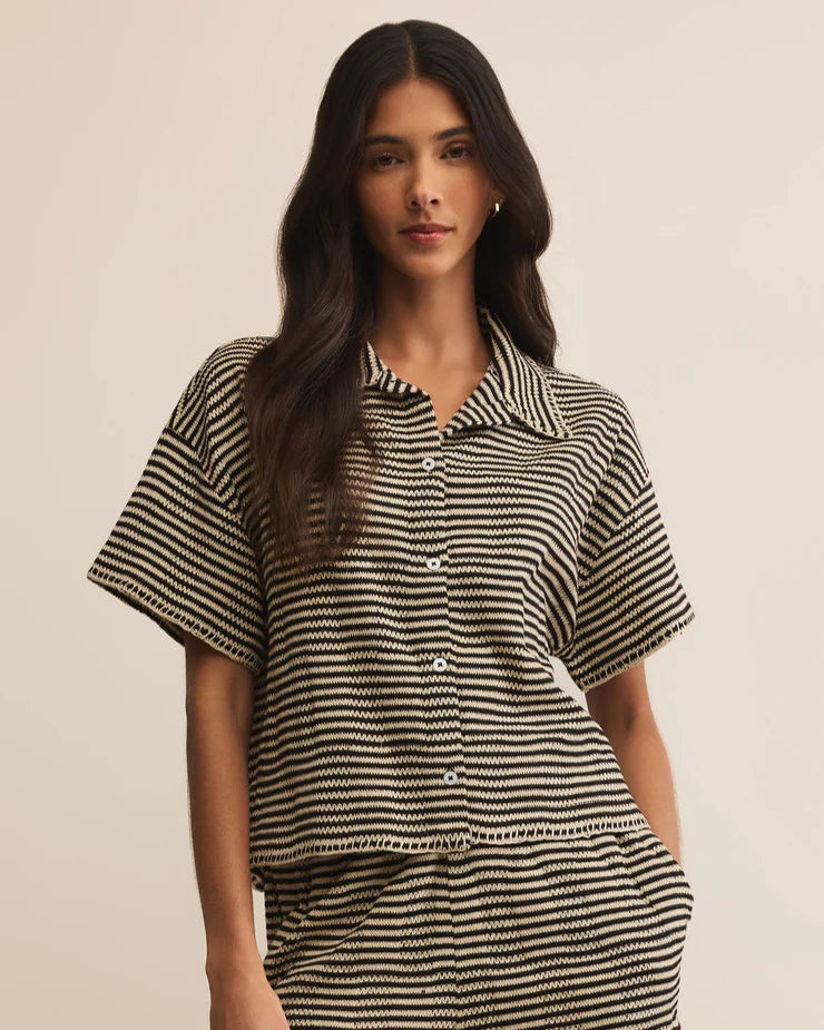 Woman wearing a black and white striped shirt and shorts set on a beige background