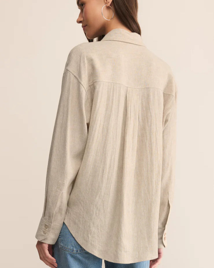 Woman wearing a beige shirt and blue jeans on a beige background