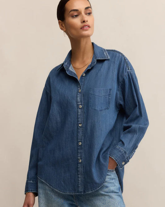 Woman wearing a blue denim shirt and jeans on a beige background