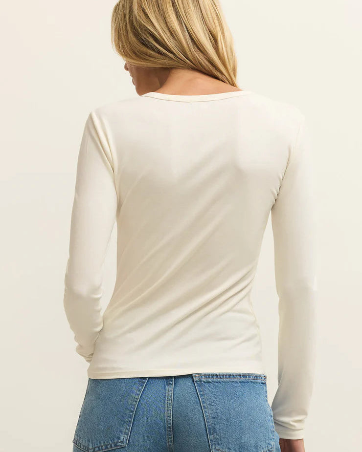 Person wearing a white long-sleeve top and blue jeans on a plain background