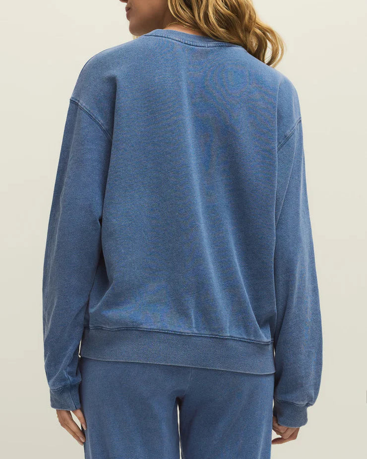 Person wearing a blue sweatshirt and pants on a beige background