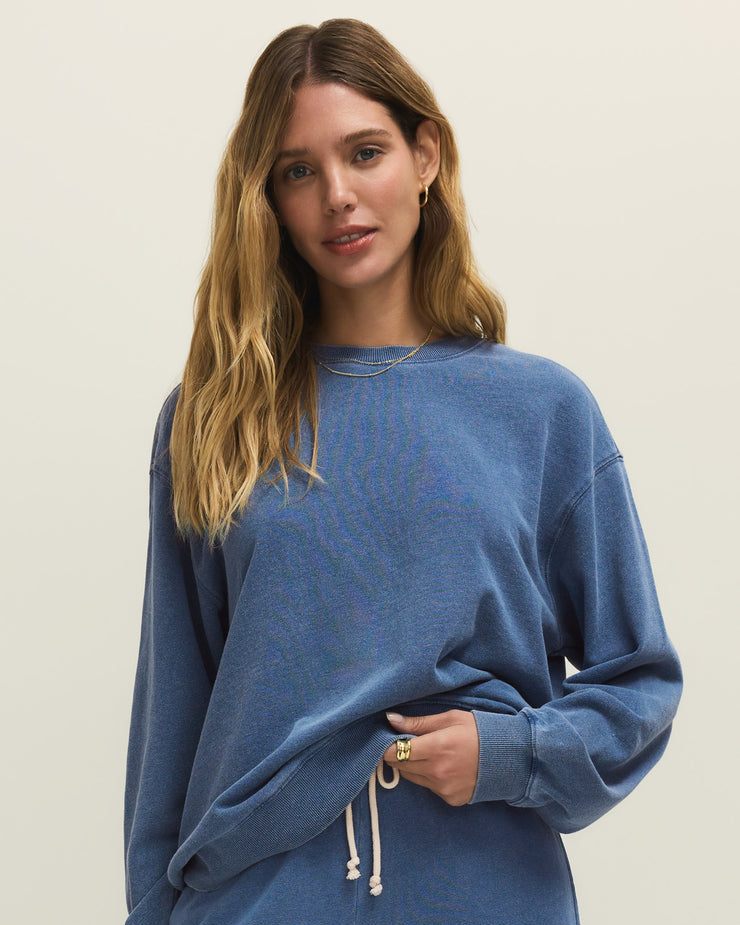 Woman wearing a blue sweatshirt and pants on a beige background