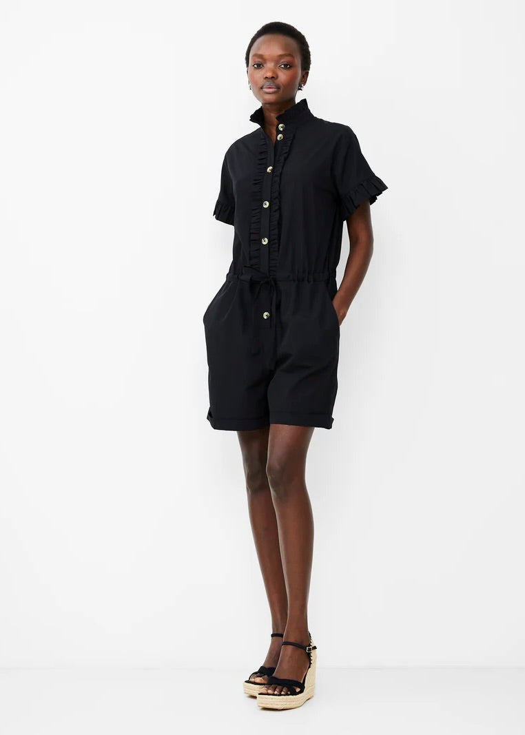 Model wearing French Connection Era Poplin Playsuit in black with hands in pockets against white background