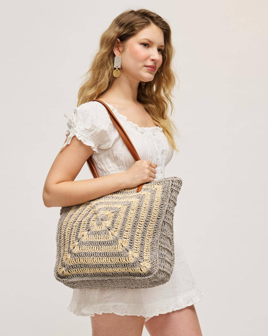 Woman holding a textured handbag against a plain background