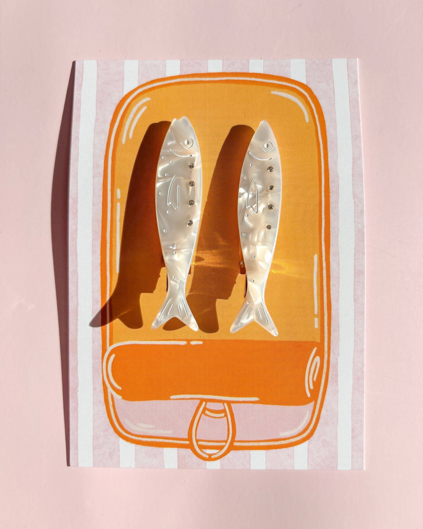 Packaged hair extensions with orange packaging on a pink background