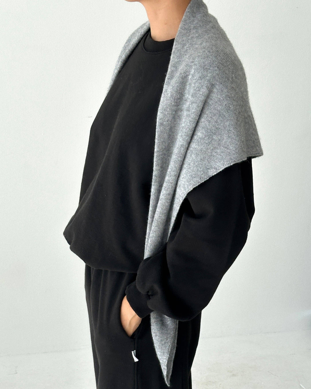 Person wearing a black outfit with a gray cardigan on a white background