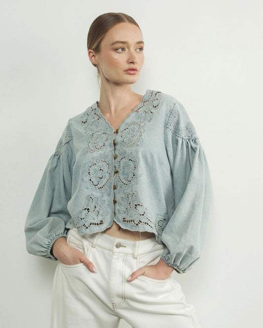 Aaron and amber denim floral embroidery blouse, woman wearing flower embroidered blouse, light blue in front of white wall puff sleeves, summery
