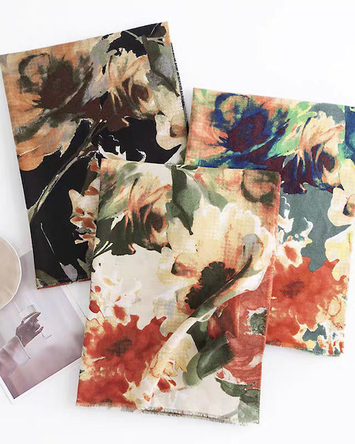 Three floral-patterned napkins on a white surface with a cup and saucer.