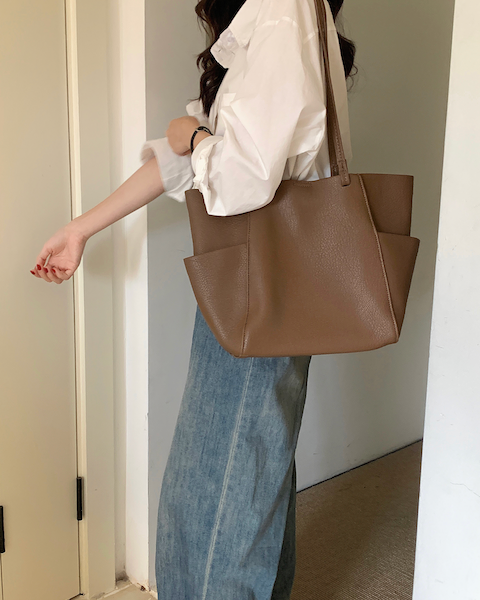 Person holding a brown tote bag in an indoor setting
