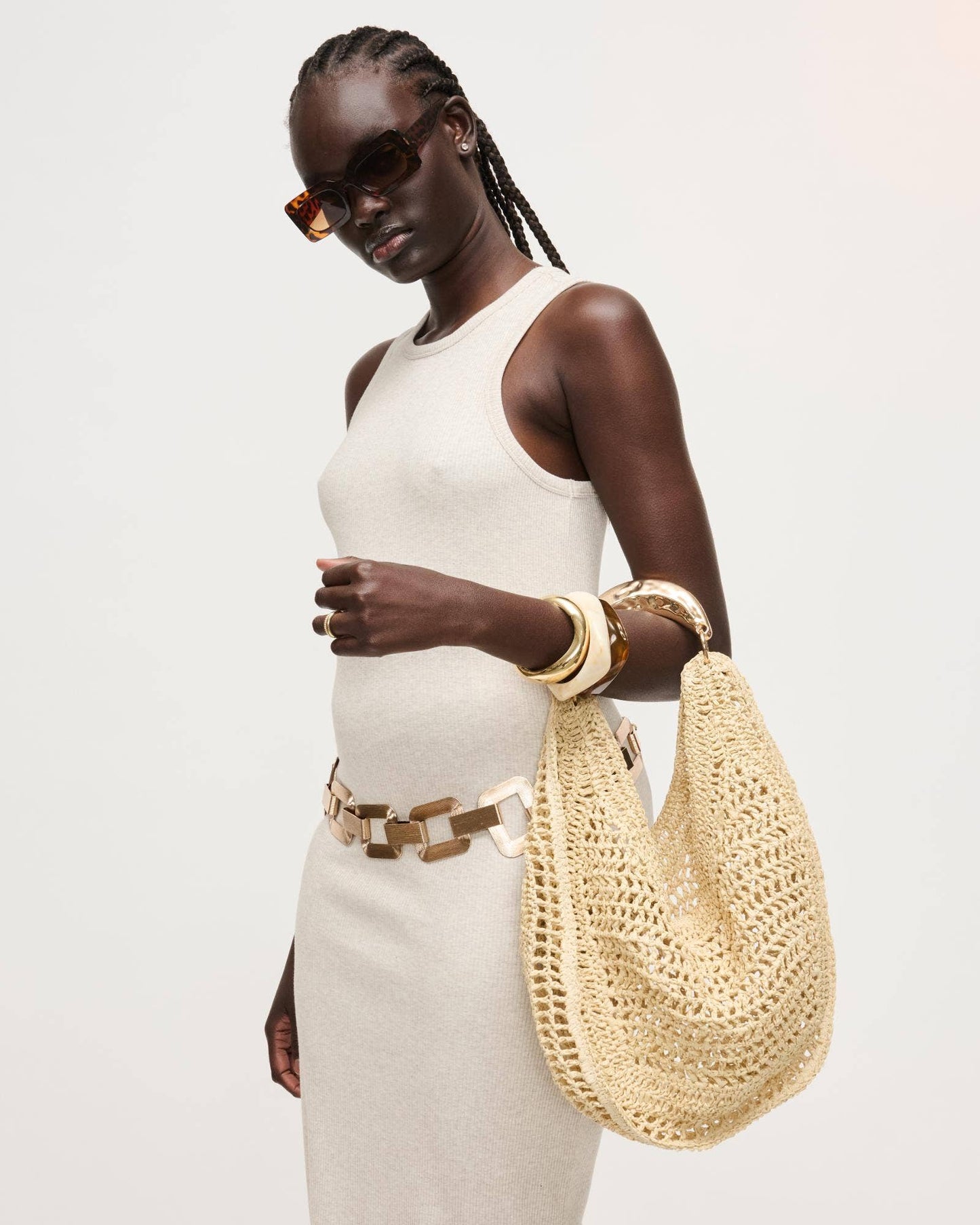Woman holding a woven handbag against a plain background