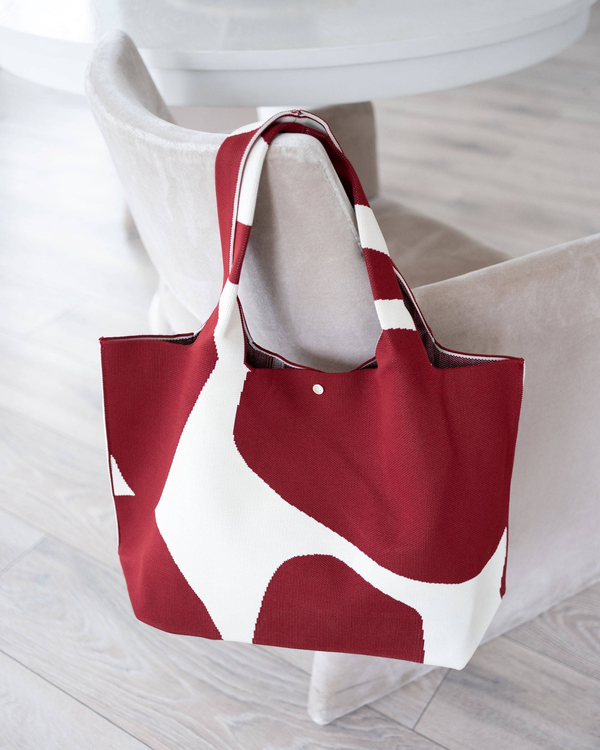 Red and white tote bag on a light wooden floor