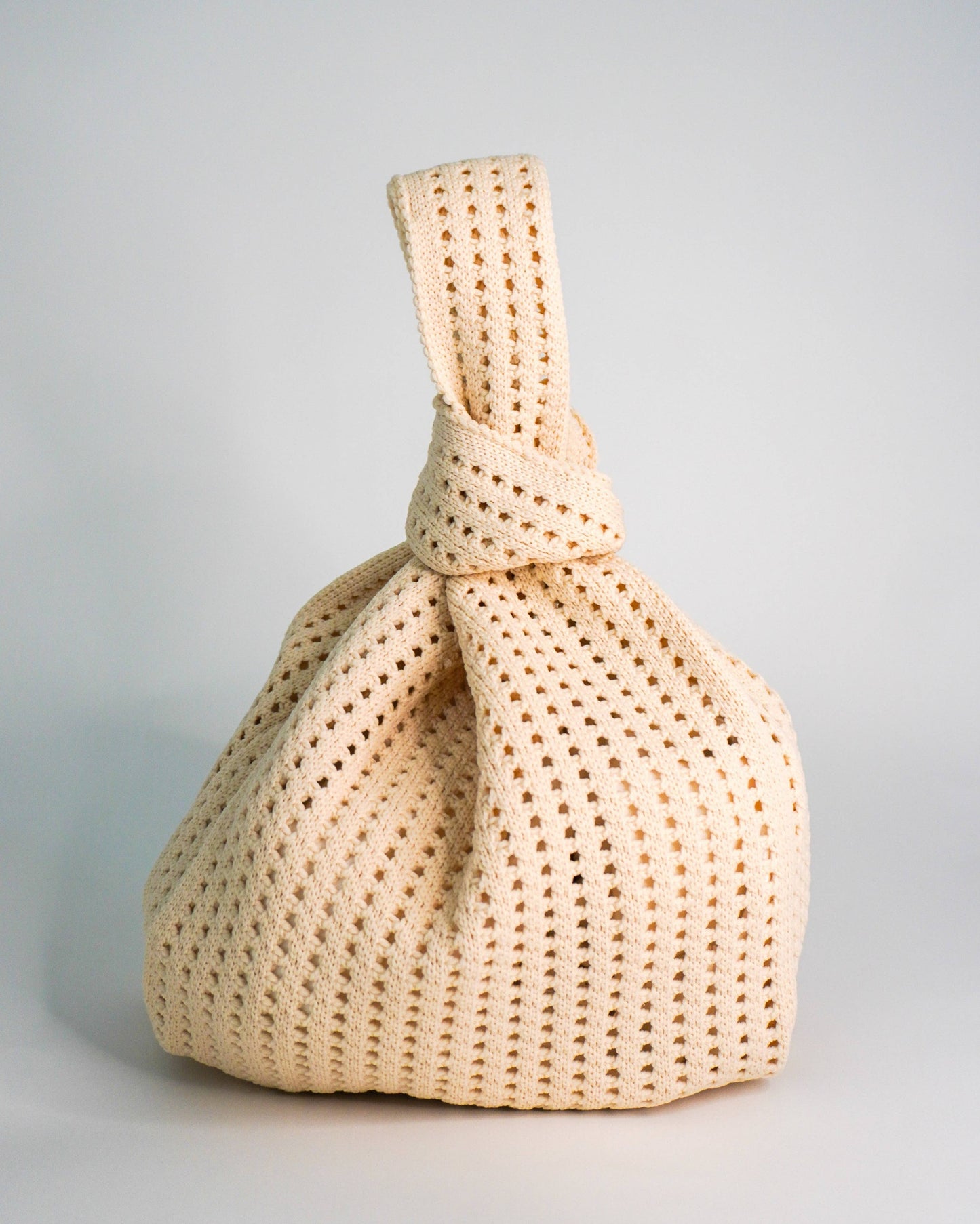 Beige woven handbag on a light gray background