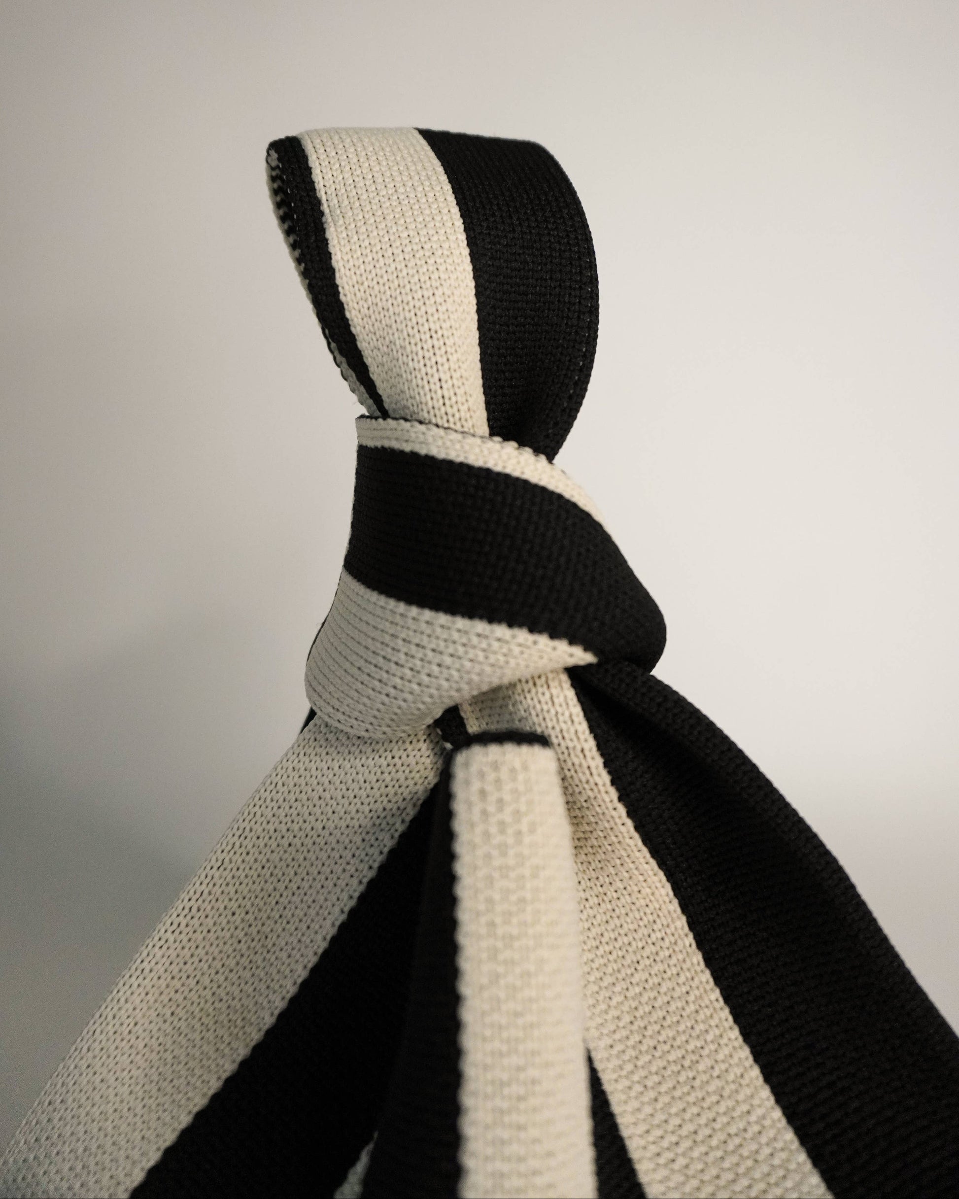 Black and white striped tie on a light gray background
