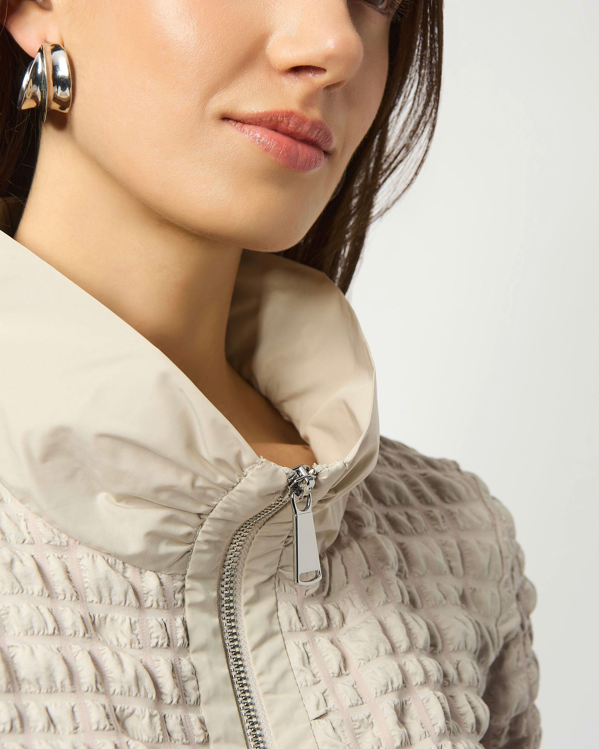 Model is wearing Joseph Ribkoff Bubble Jacquard A-Line Top in color moonstone with silver earrings on a white background