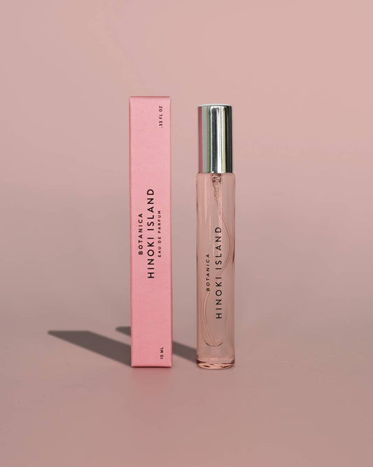 Botanica Hinoki Island perfume bottle and packaging on a pink background