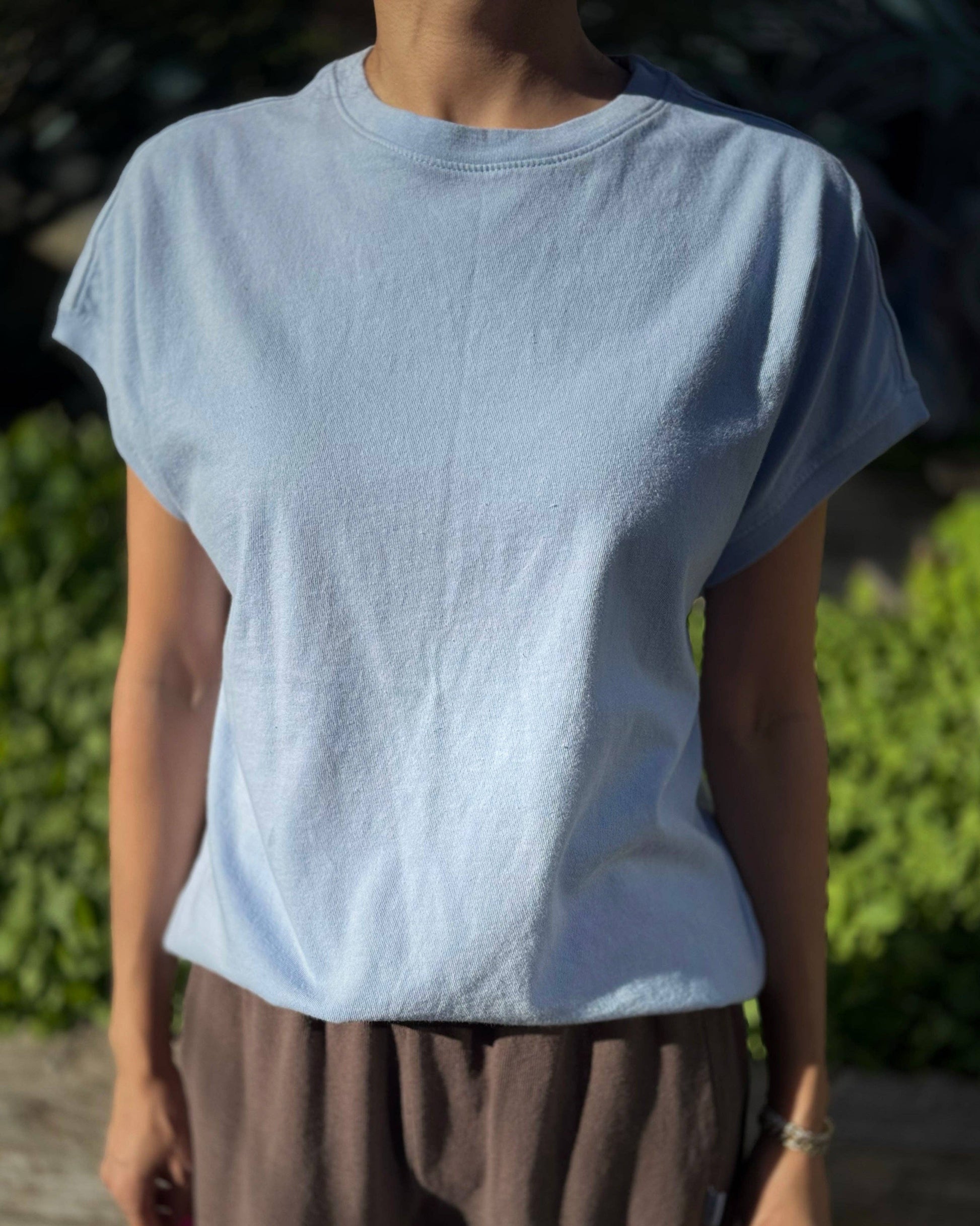 Person wearing a light blue t-shirt and brown pants outdoors