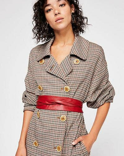 Woman wearing a plaid coat with a red belt against a white background