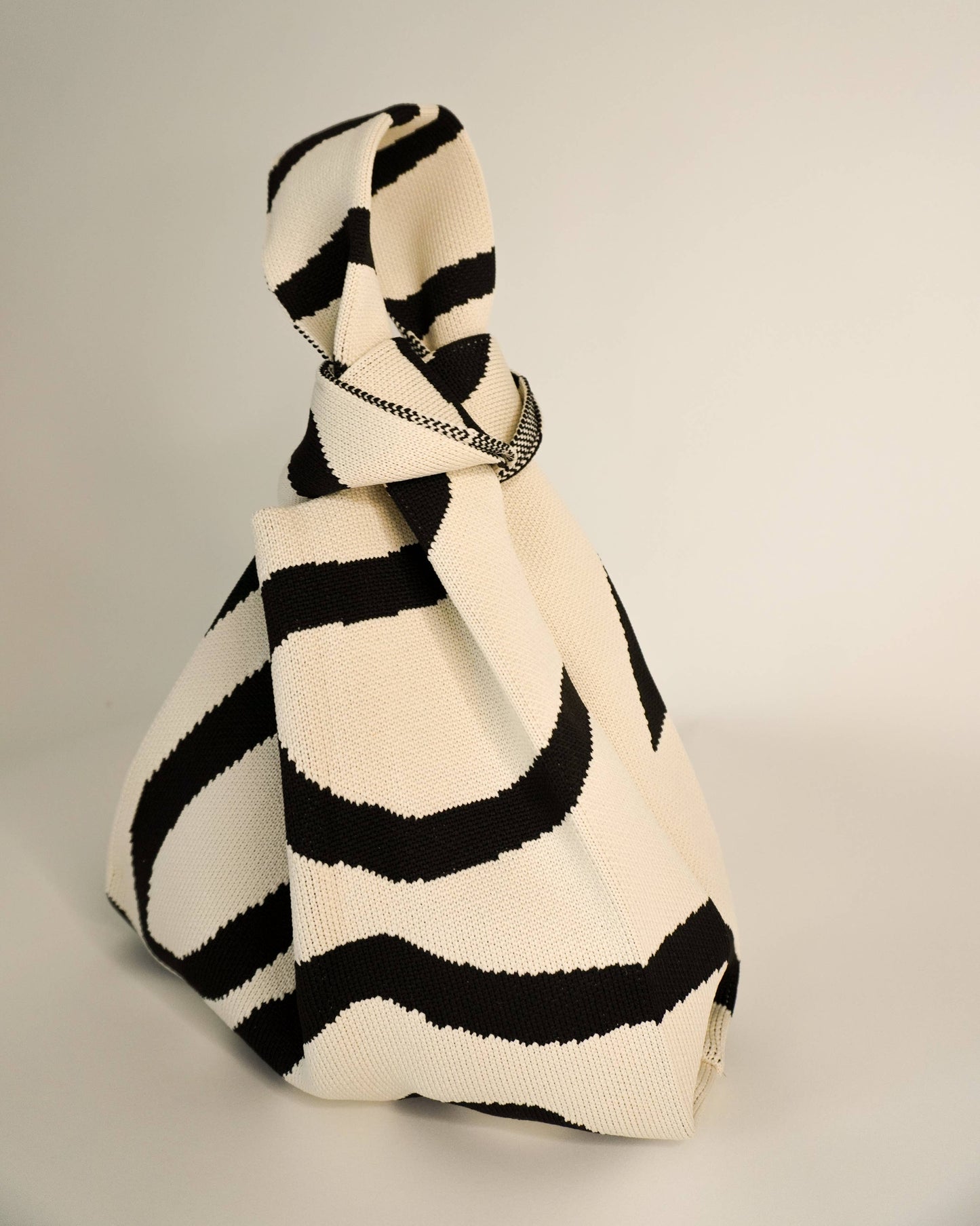 Black and white striped handbag on a gray background