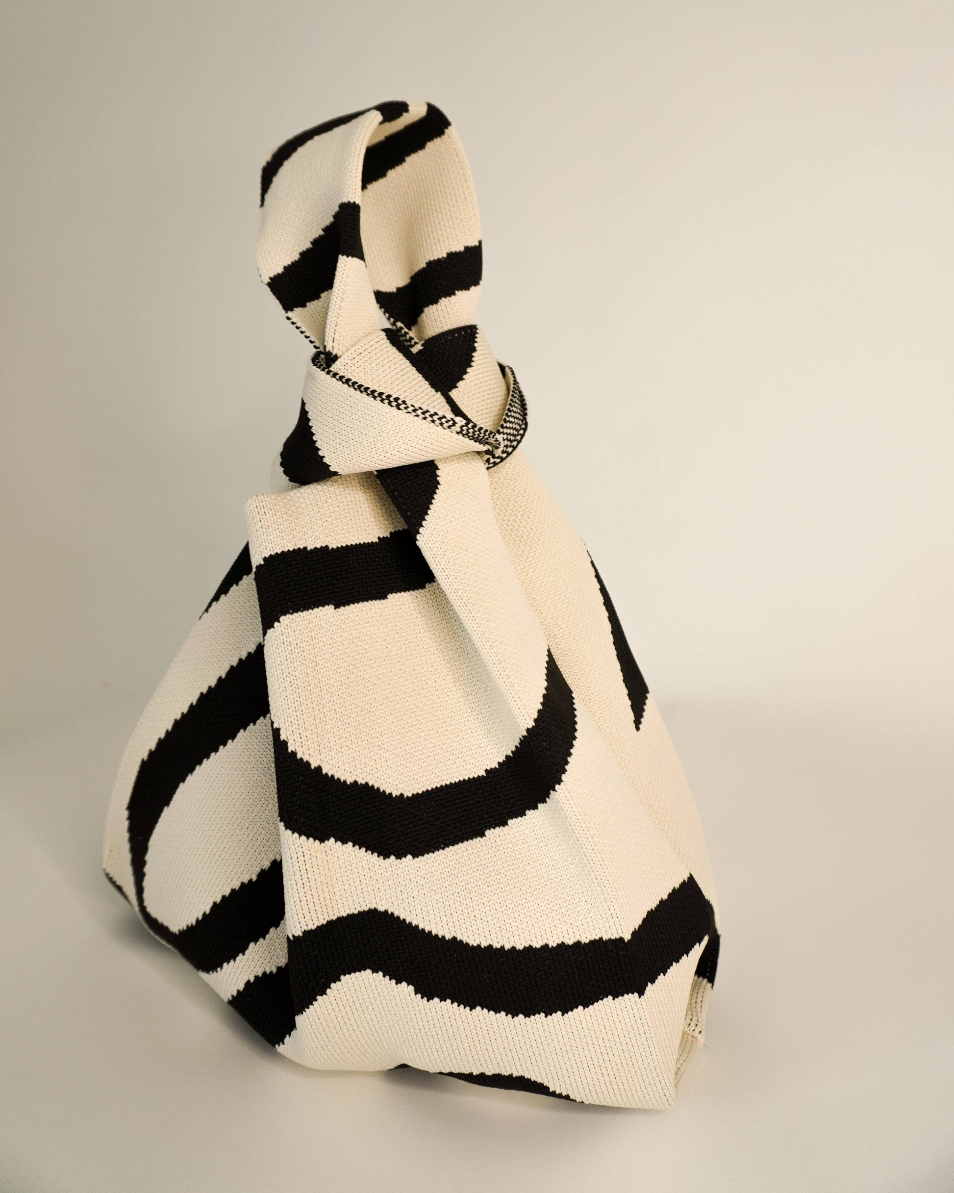 Black and white striped handbag on a gray background