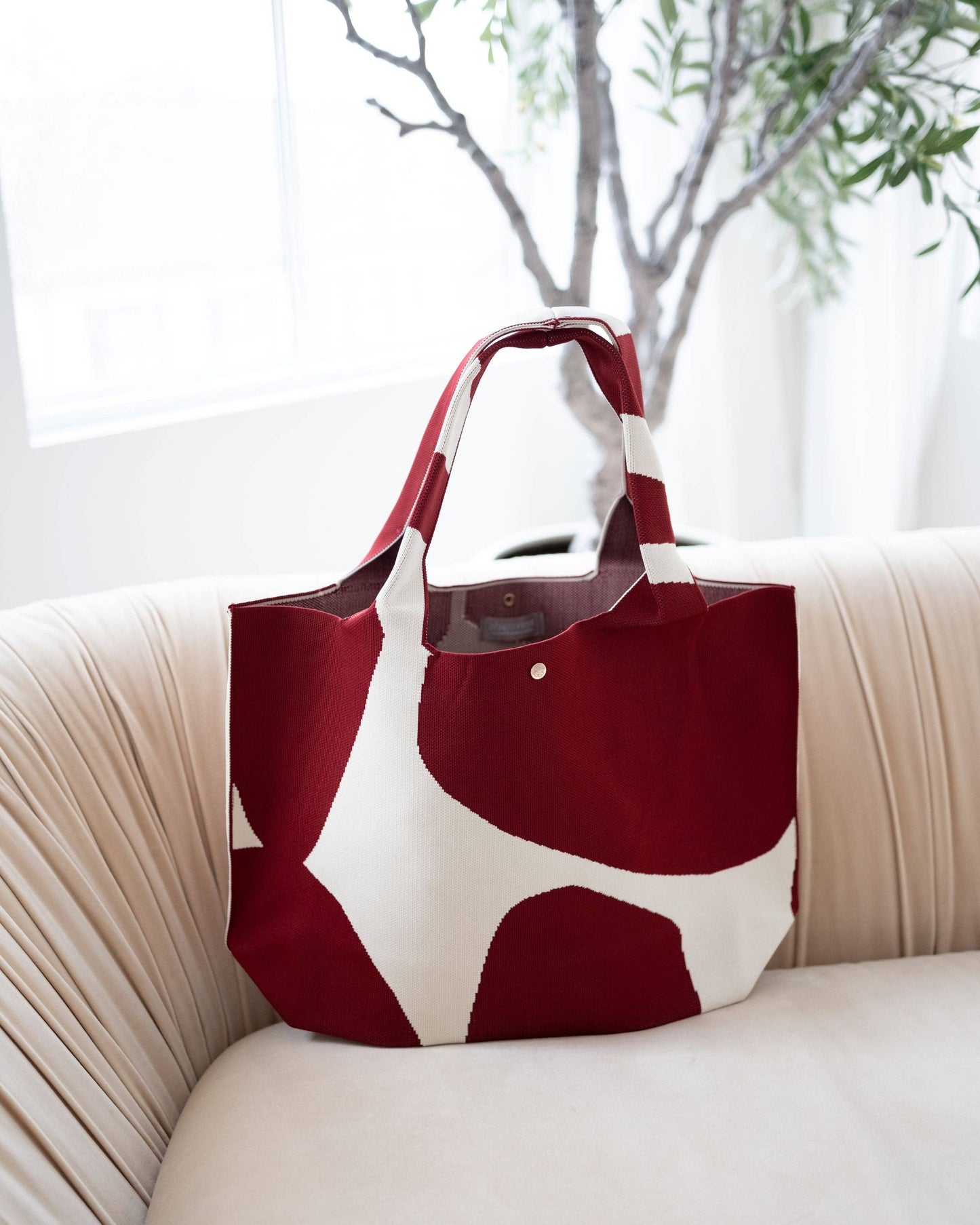Red and white tote bag on a beige couch with a blurred indoor background