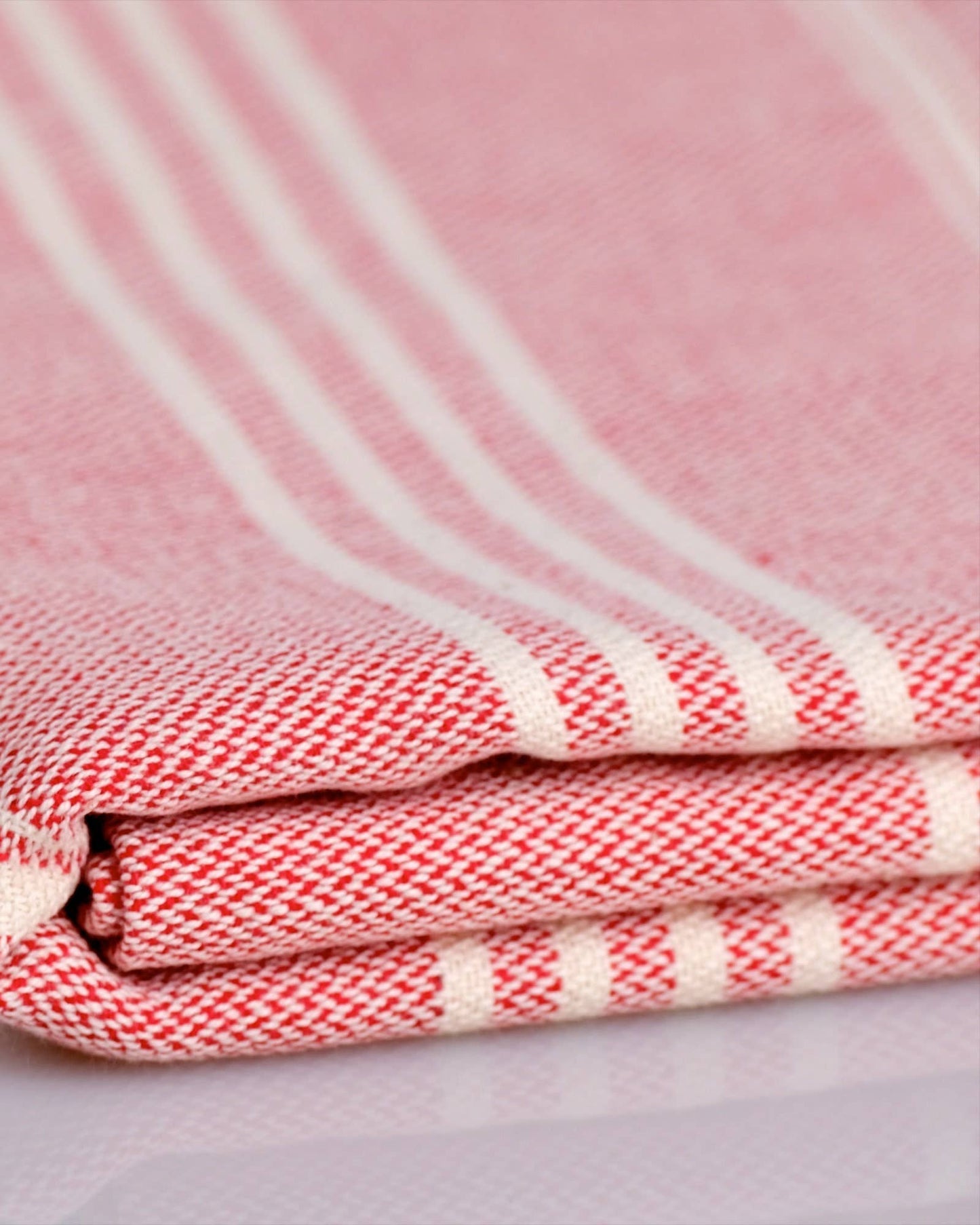 Folded pink and white striped towel with Kalliston logo in the corner