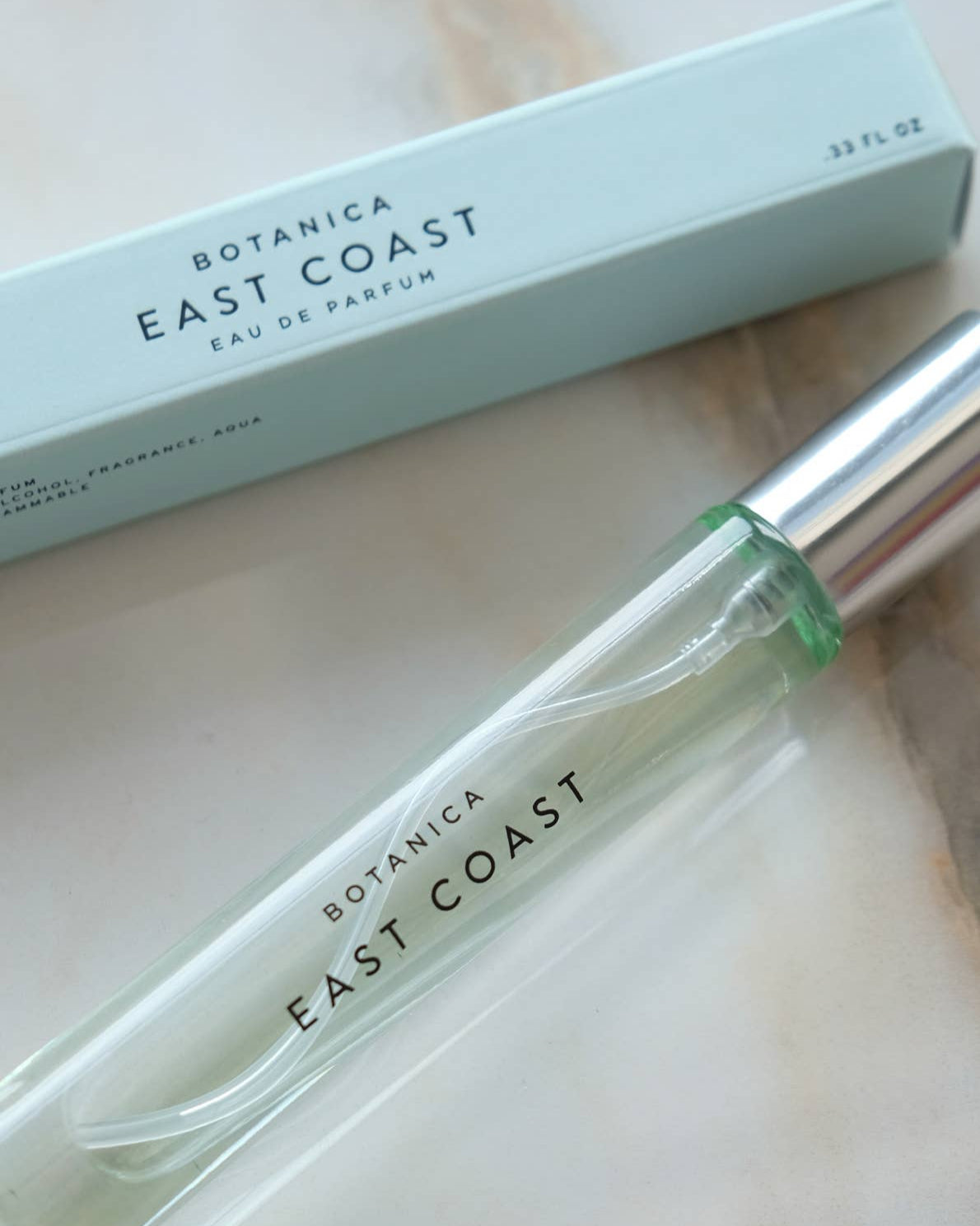 Perfume bottle and packaging of Botanica East Coast on a light background